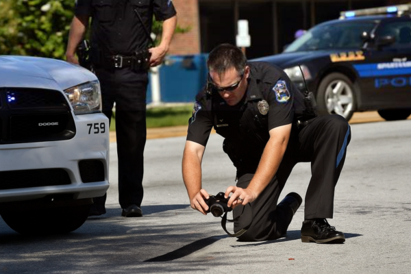 A crash investigator for a police department photographs a skid mark left behind on the roadway.
